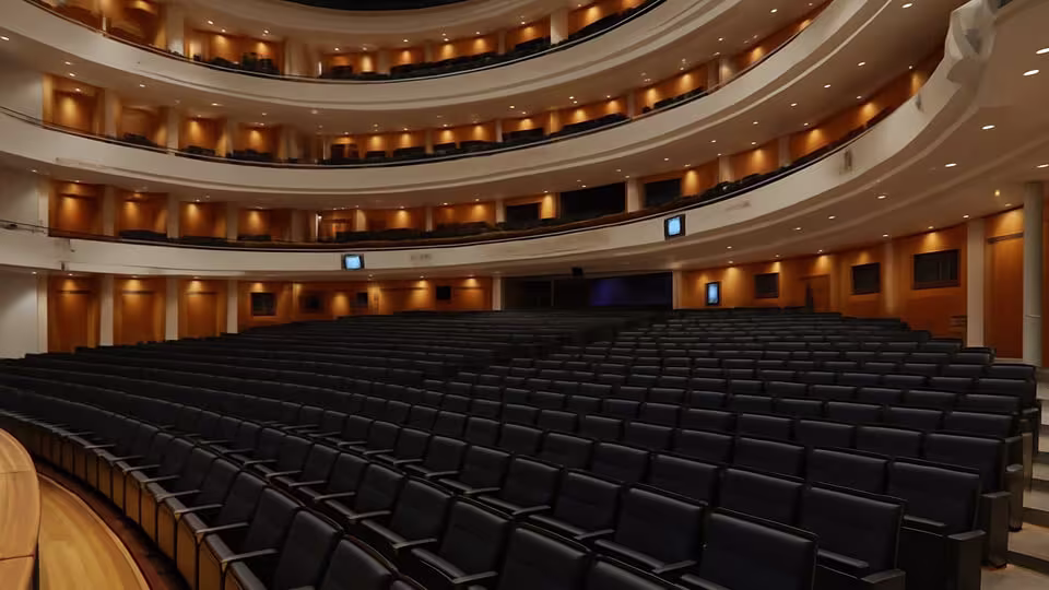 Weitwinkelaufnahme des Hauptsaals der Finnischen Nationaloper in Helsinki mit gestufter Sitzanordnung und warmer Beleuchtung.
